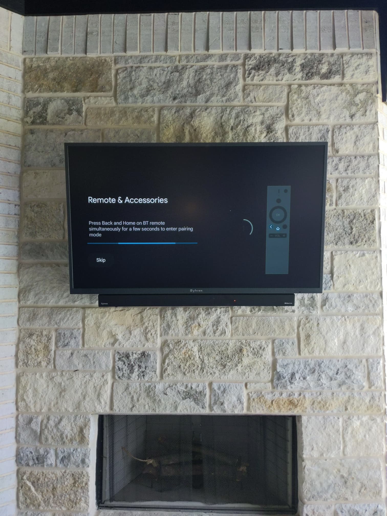 Television and soundbar mounted above a stone fireplace